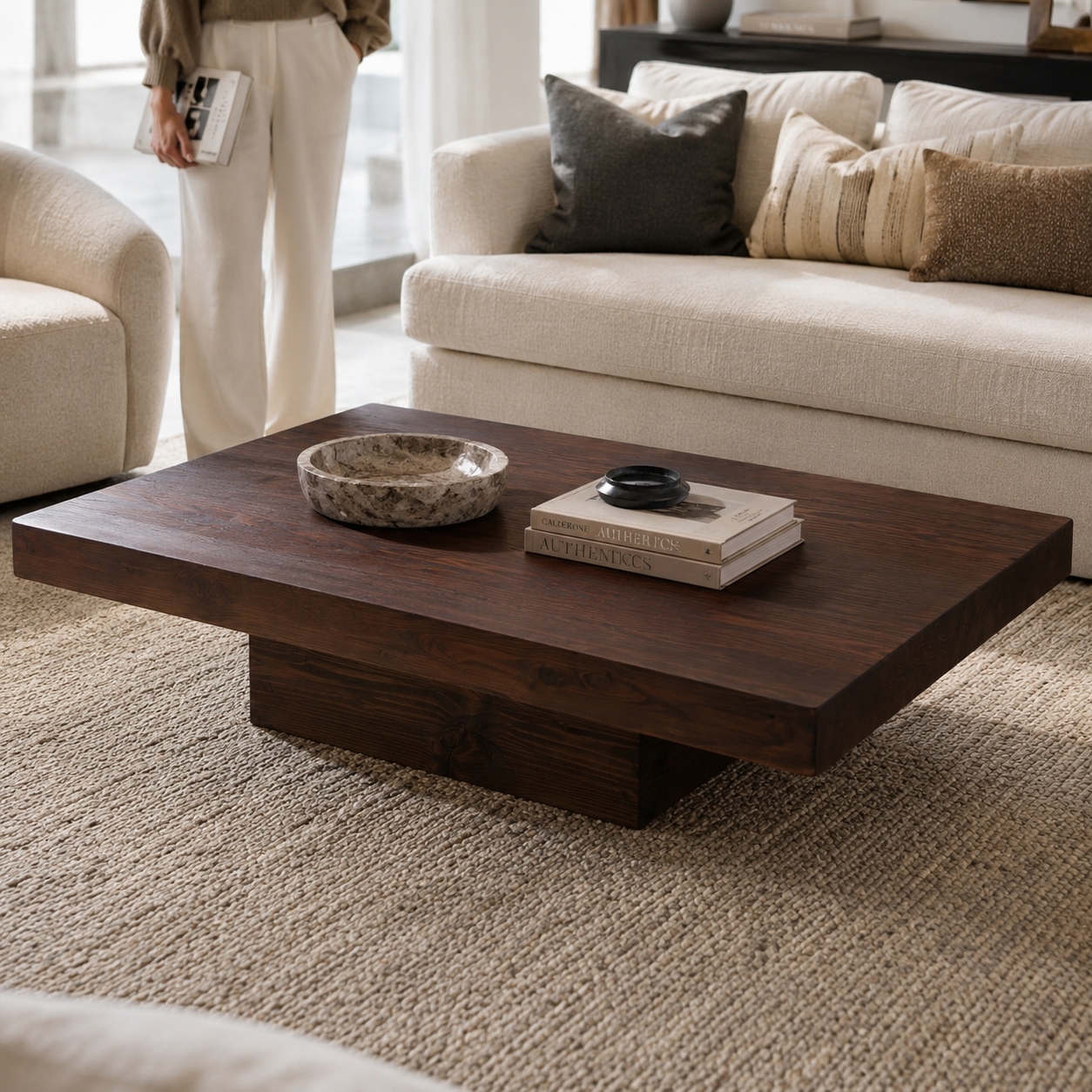 Dark wood sculptural plinth coffee table shown in a refined living room setting for scale